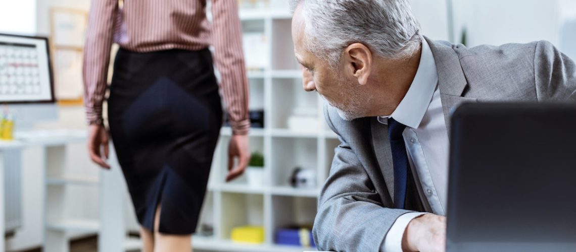 Beaming old man. Inappropriate senior worker actively turning around while female colleague passing by in skirt