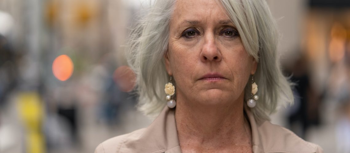 Mature caucasian woman in city serious face portrait on a street