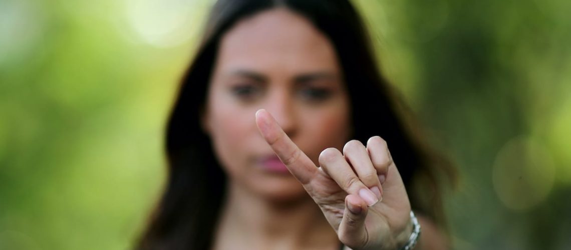 Woman annoyed making stop sign with hand, saying no, expressing defense or restriction.