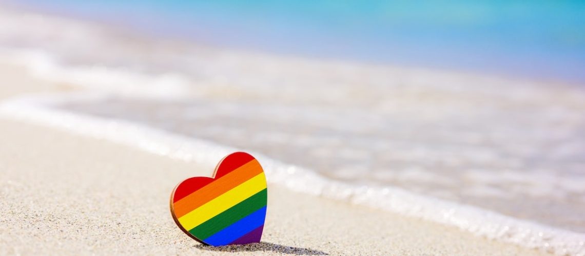 LGBT heart on the sandy beach against the background of the sea. Concept of the best resort for lgbt couples