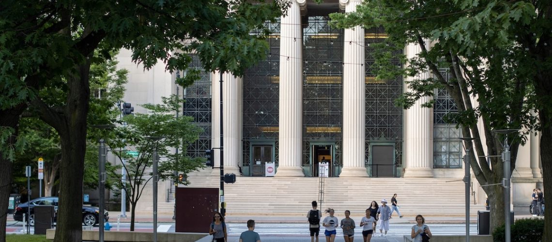 Cambridge, MA, USA - June 28, 2022: Students on the campus of the Massachusetts Institute of Technology in Cambridge, Massachusetts. Rogers Building (MIT Building 7) is seen in the background.